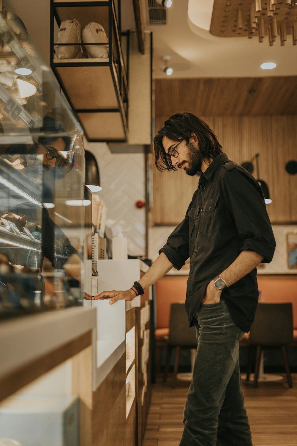 man in black button up shirt and gray denim jeans holding clear glass bottle