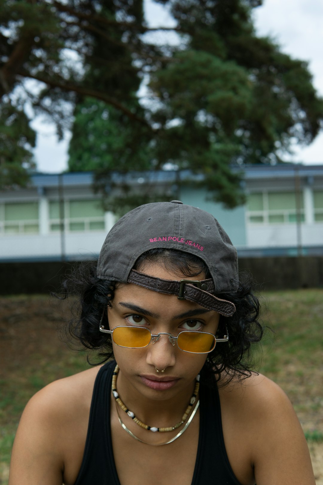 woman in black tank top wearing gray cap and yellow framed sunglasses