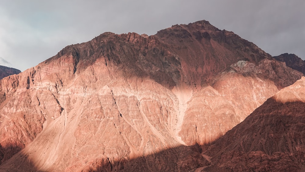 brown rocky mountain under gray sky