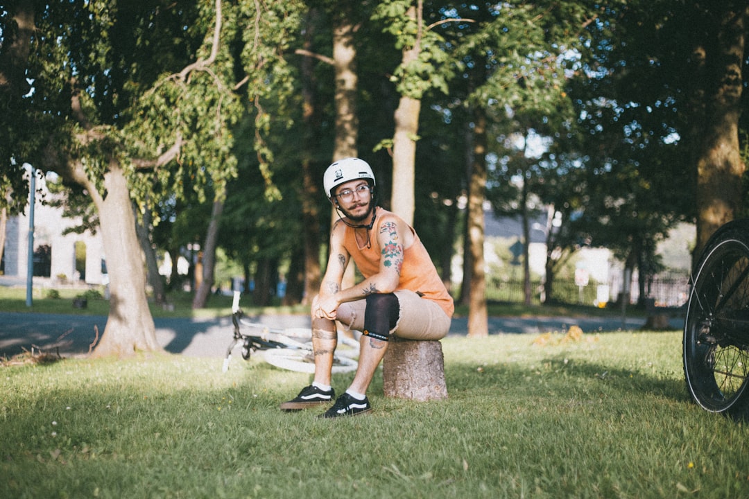 woman in orange sports bra and black shorts sitting on green grass field during daytime