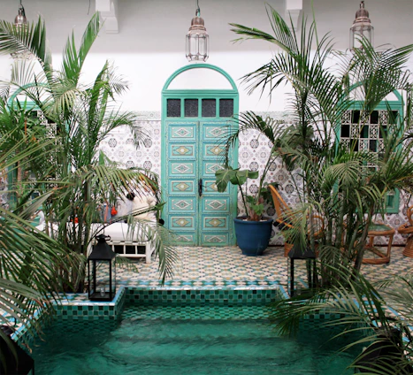 A serene Moroccan courtyard bathed in warm golden light, showcasing intricate tilework and lush greenery.