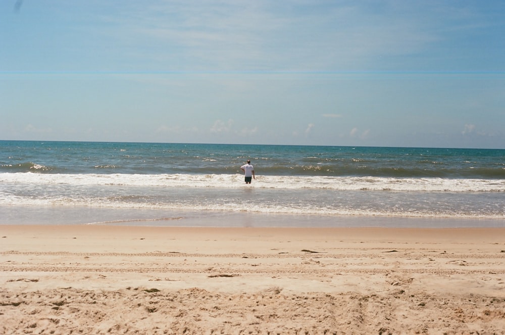 Person im weißen Hemd tagsüber am Strand spazieren