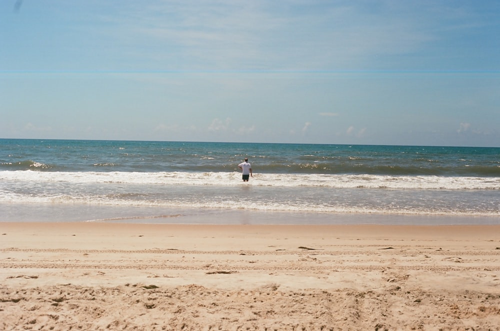 person in white shirt walking on beach during daytime