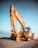yellow excavator on gray rock near body of water during daytime