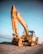 yellow excavator on gray rock near body of water during daytime