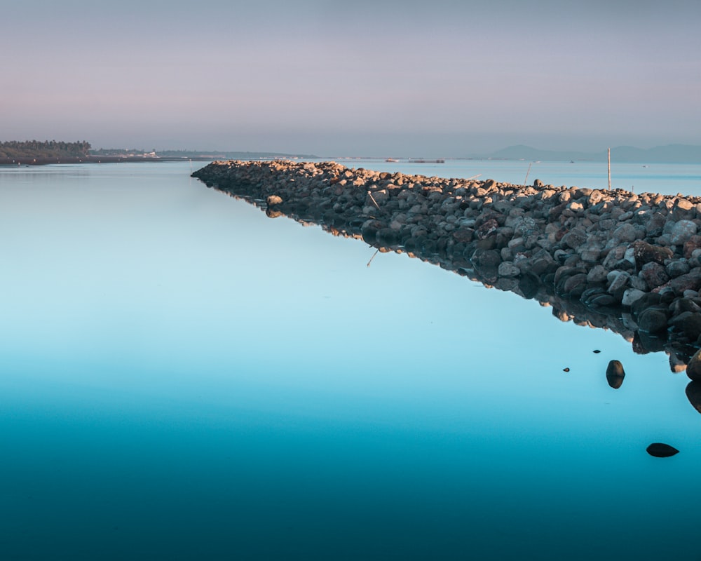 Formación rocosa gris al lado del cuerpo de agua durante el día