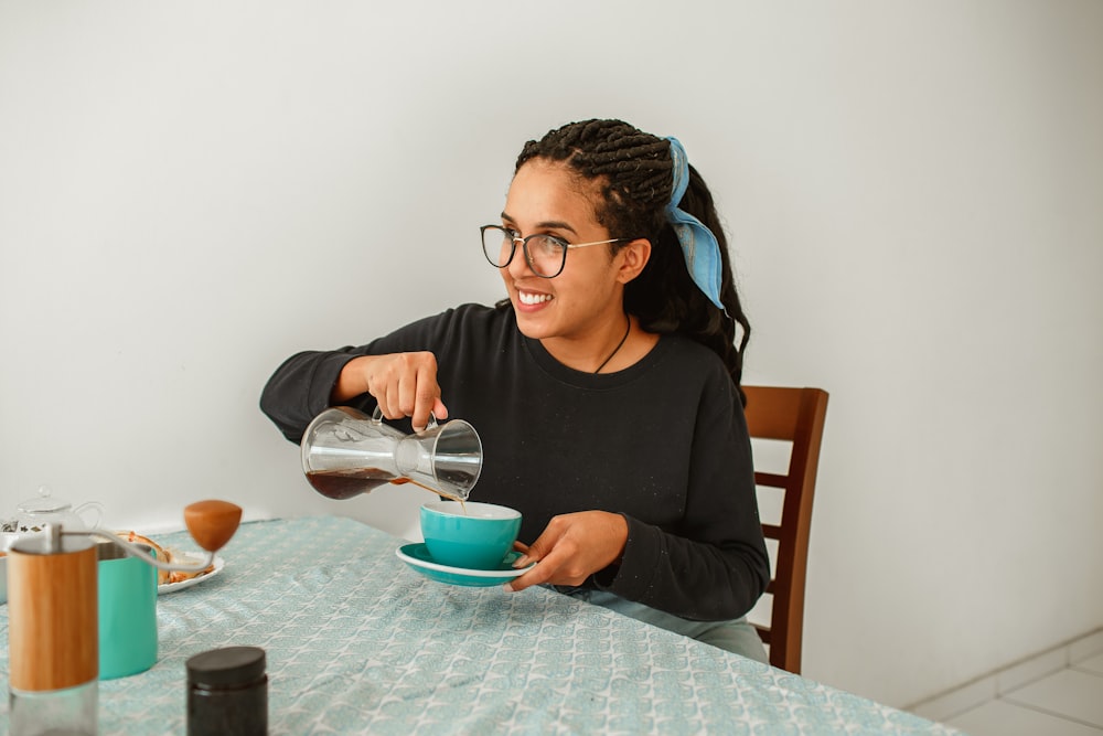 woman in black long sleeve shirt holding clear glass mug