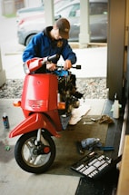 A friendly mechanic adjusting a moped engine in a bright workshop.