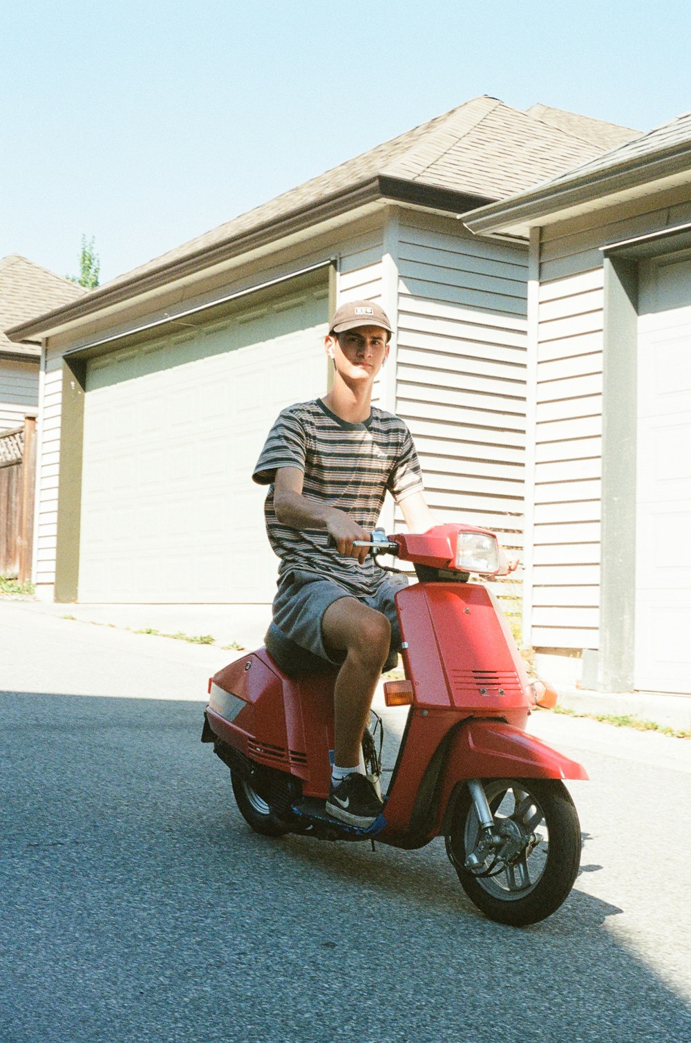 man in black and white stripe polo shirt riding red motor scooter