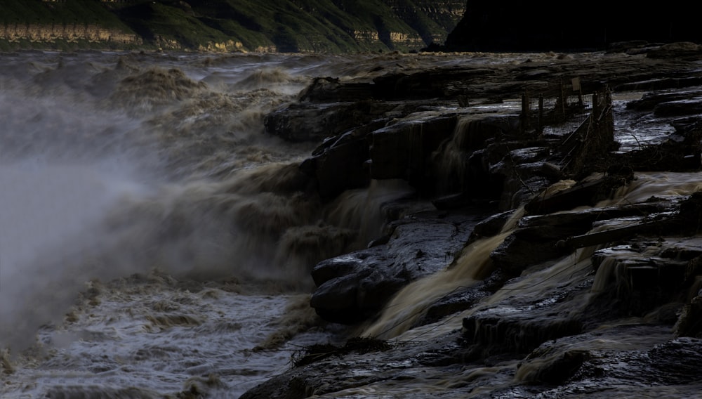 water falls on rocky mountain during daytime