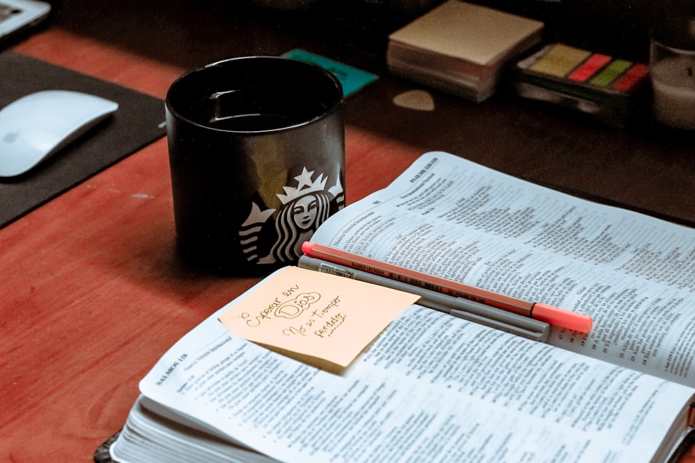 black and white floral ceramic mug beside white printer paper on brown wooden table