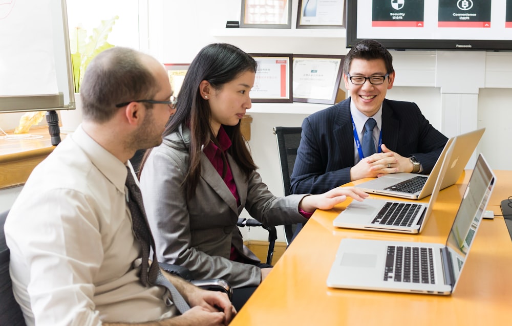 man and woman sitting at the table using macbook