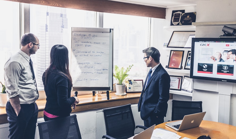 man in black jacket standing beside white board