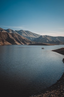 person in boat on lake near mountains during daytime