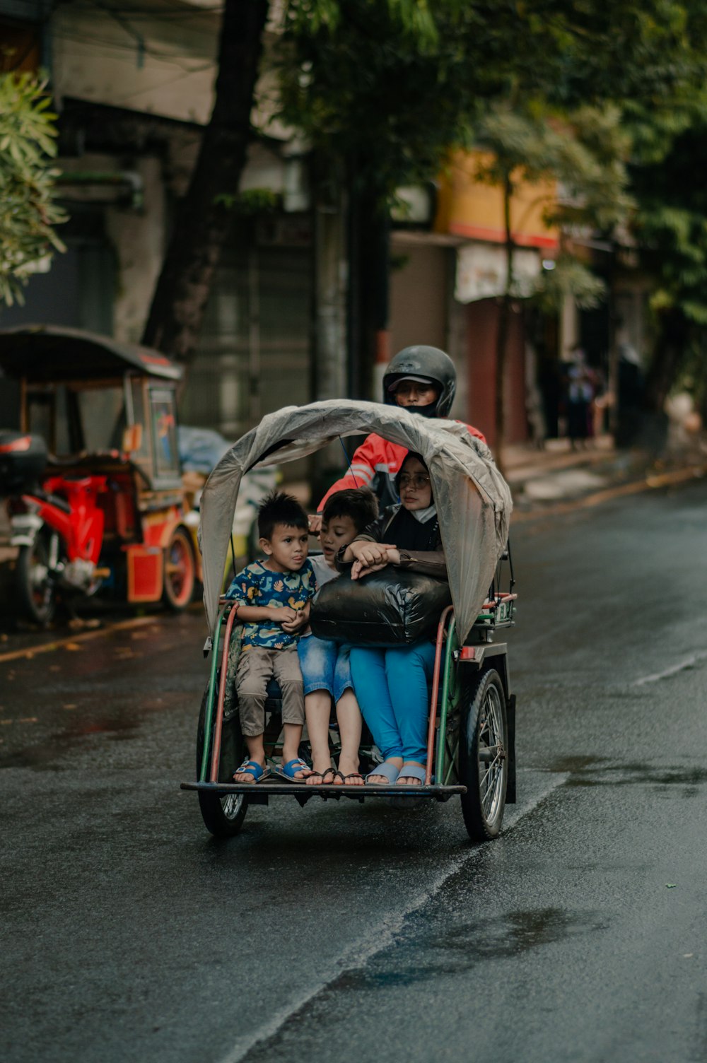 man in blue jacket and blue denim jeans riding on red and black auto rickshaw