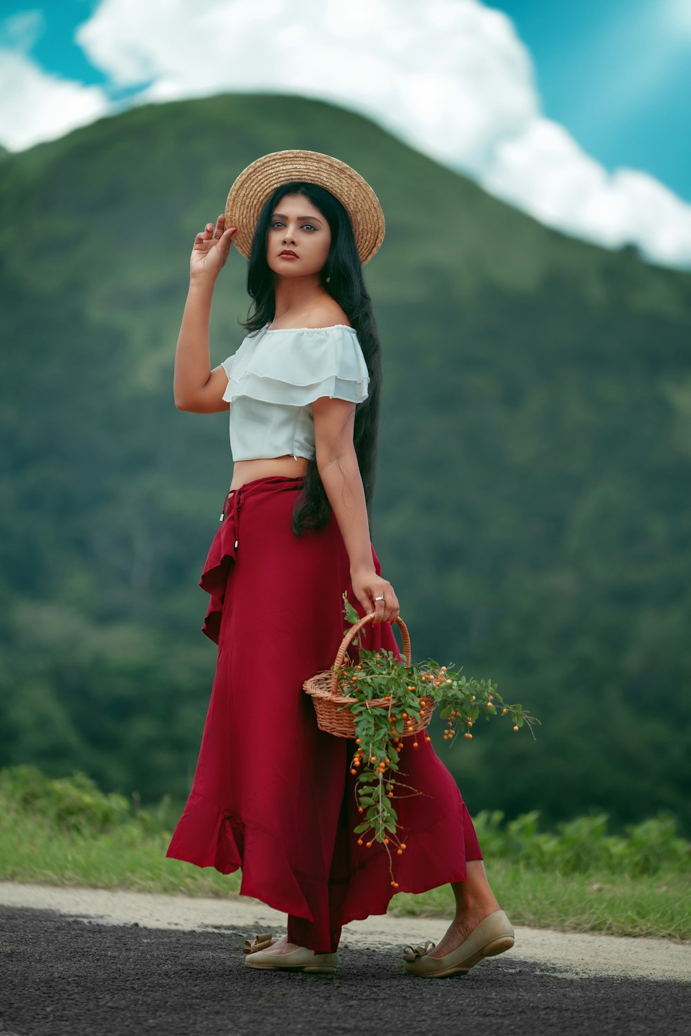 woman in white shirt and red skirt holding brown woven basket