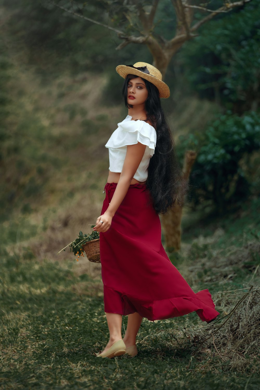 woman in white shirt and red skirt holding brown woven basket