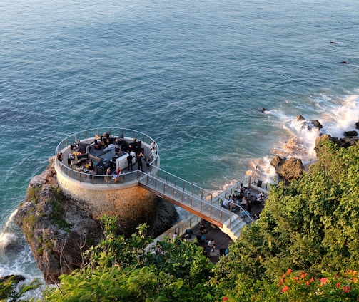 people walking on gray concrete bridge over blue sea during daytime