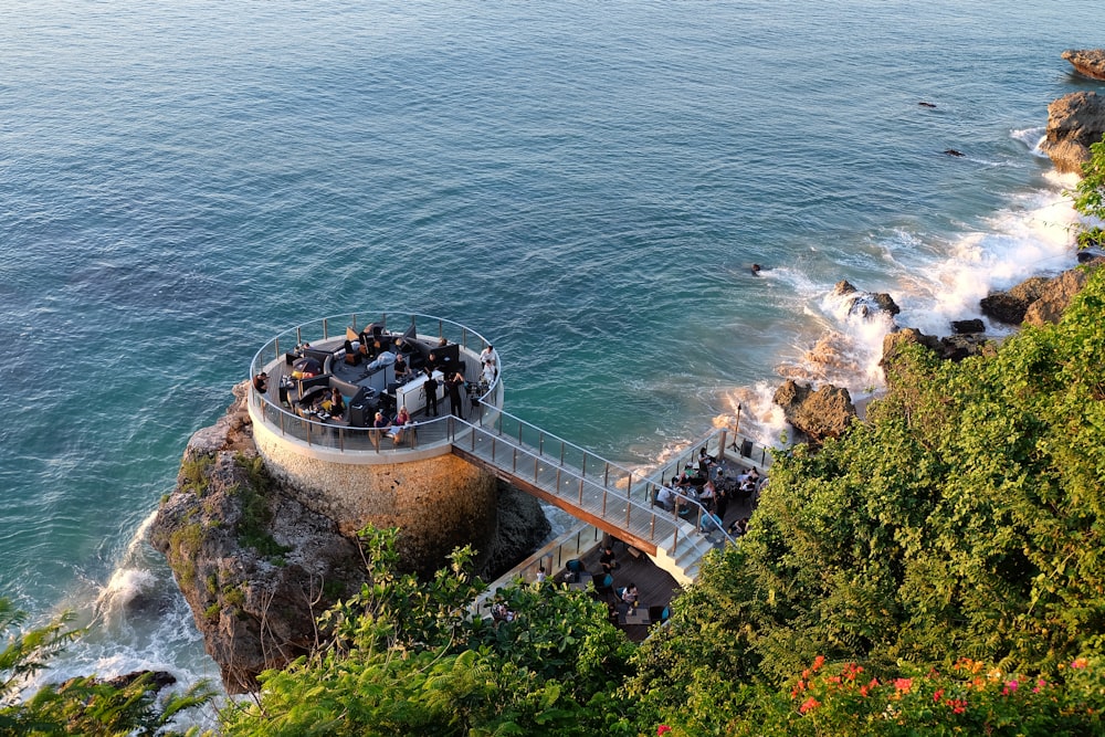 people walking on gray concrete bridge over blue sea during daytime