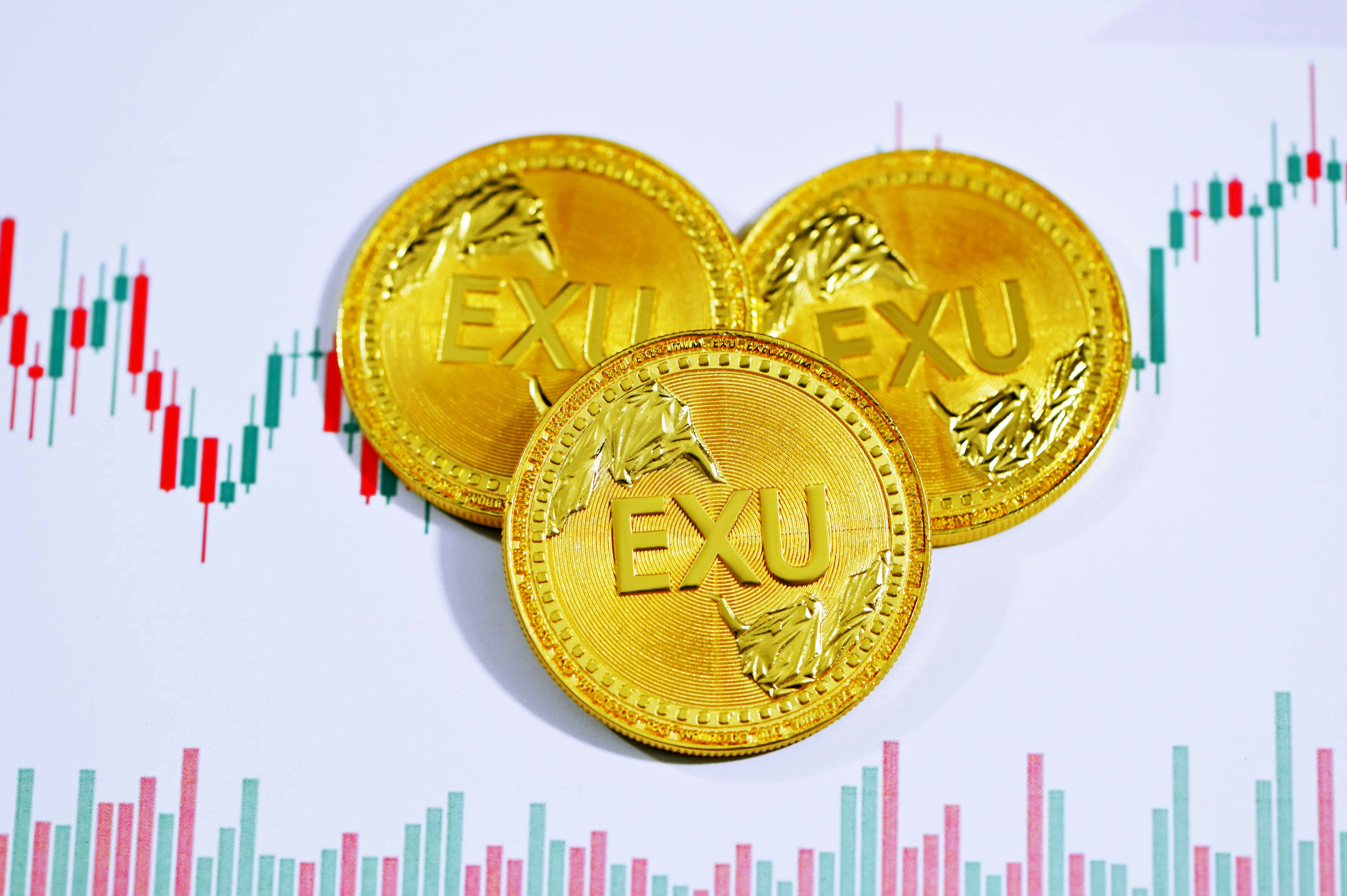 Three EXU coins on top of a trading chart
