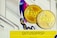 Two gold coins with the letters 'EXU' embossed on them are placed against a colorful, abstract geometric background. In the foreground, a yellow strip with the code 'QVTU5QPRSP' is visible, possibly indicating an affiliate or promotional code.