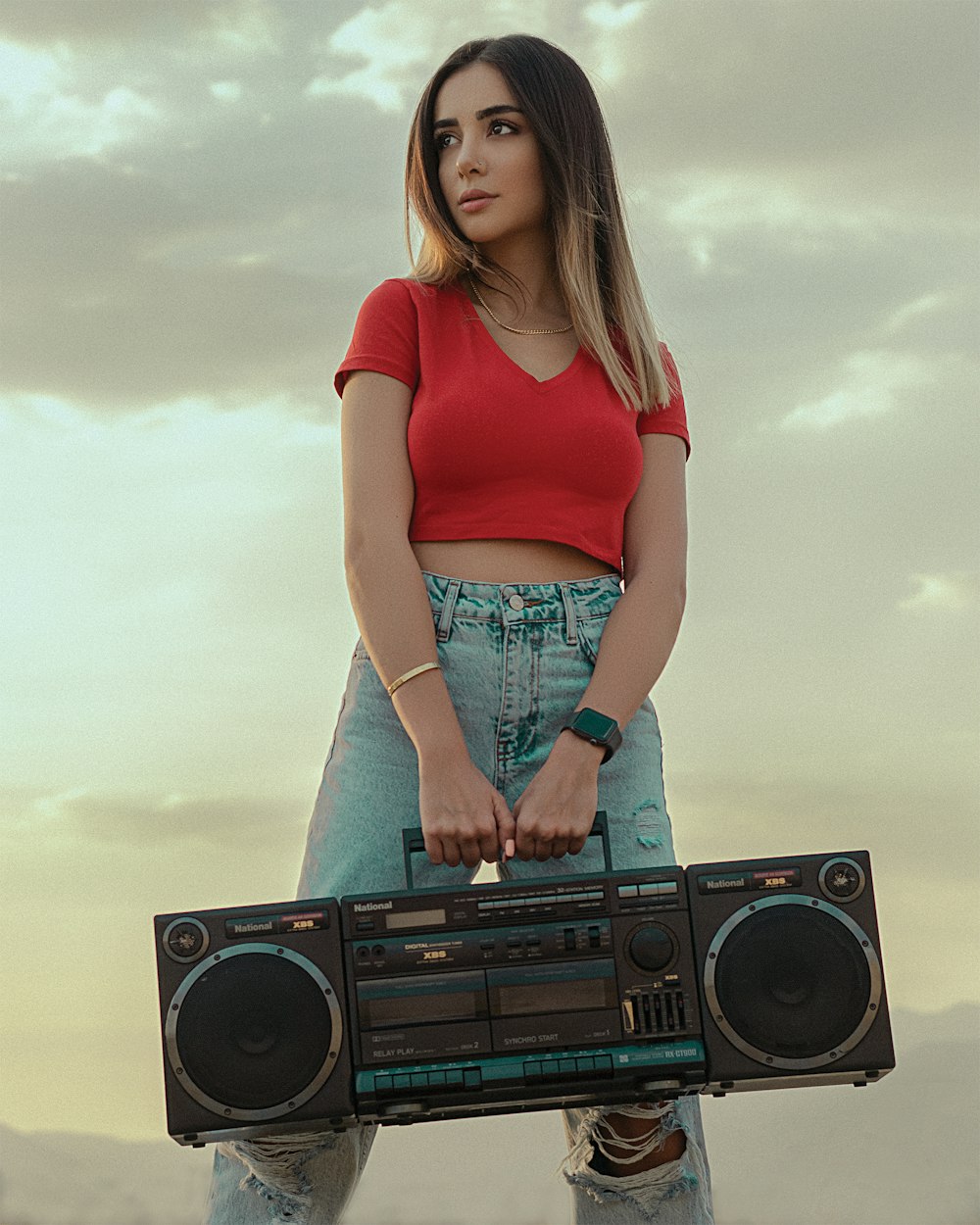 woman in red tank top and blue denim shorts standing beside black and silver radio