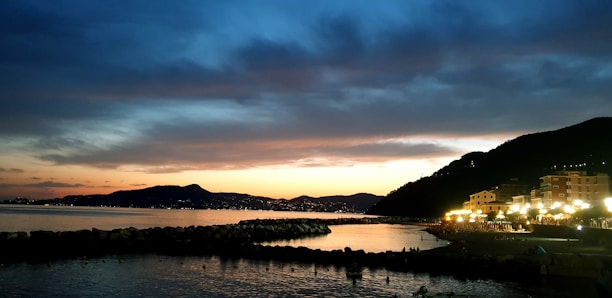 Romantic seaside resort with golden lights reflecting on calm ocean waters at dusk.