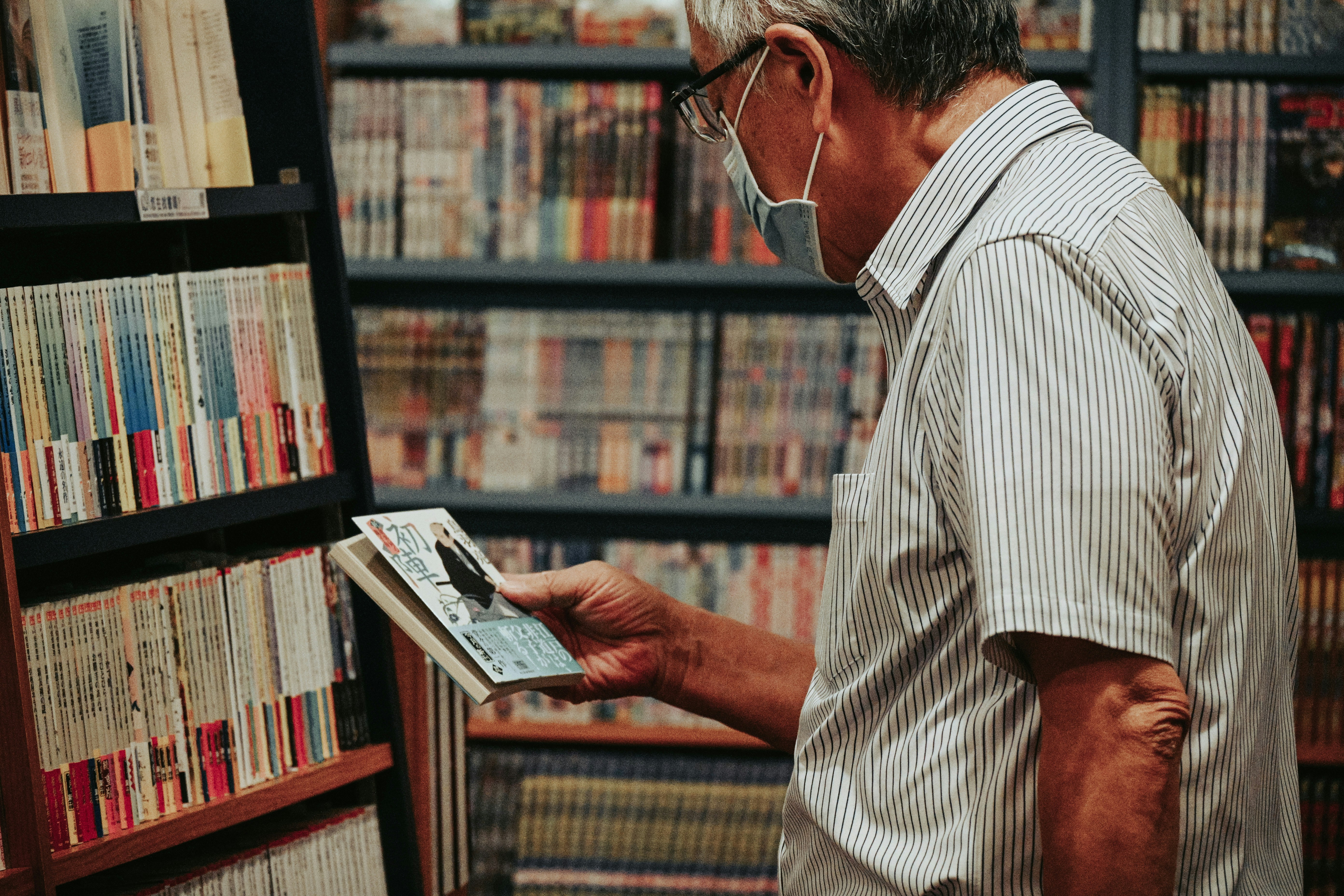 man in white and black stripe button up shirt wearing eyeglasses reading book