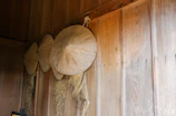 Straw hats hanging on a rustic wall, showcasing their intricate plaiting.