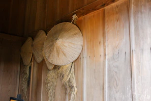 Straw hats hanging on a rustic wall, showcasing their intricate plaiting.