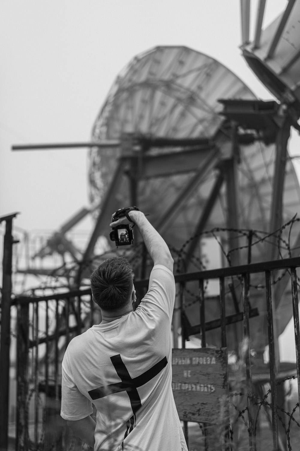 uomo in camicia bianca a maniche lunghe che scatta foto del ponte di metallo