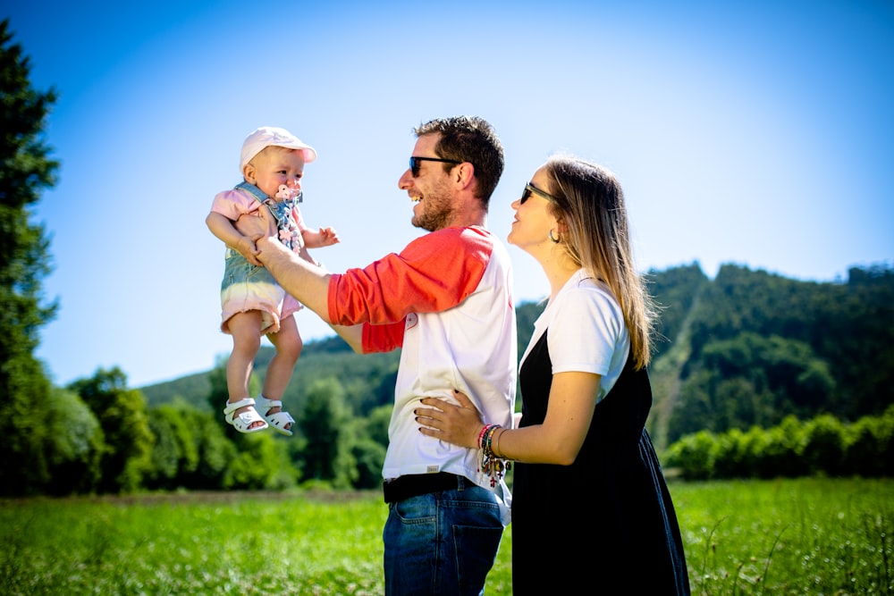 man in white and red polo shirt carrying girl in blue denim jeans during daytime