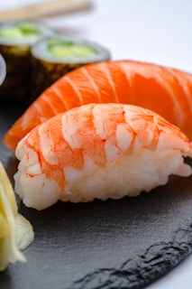 Close-up of vibrant nigiri sushi pieces artfully arranged on a minimalist black plate.