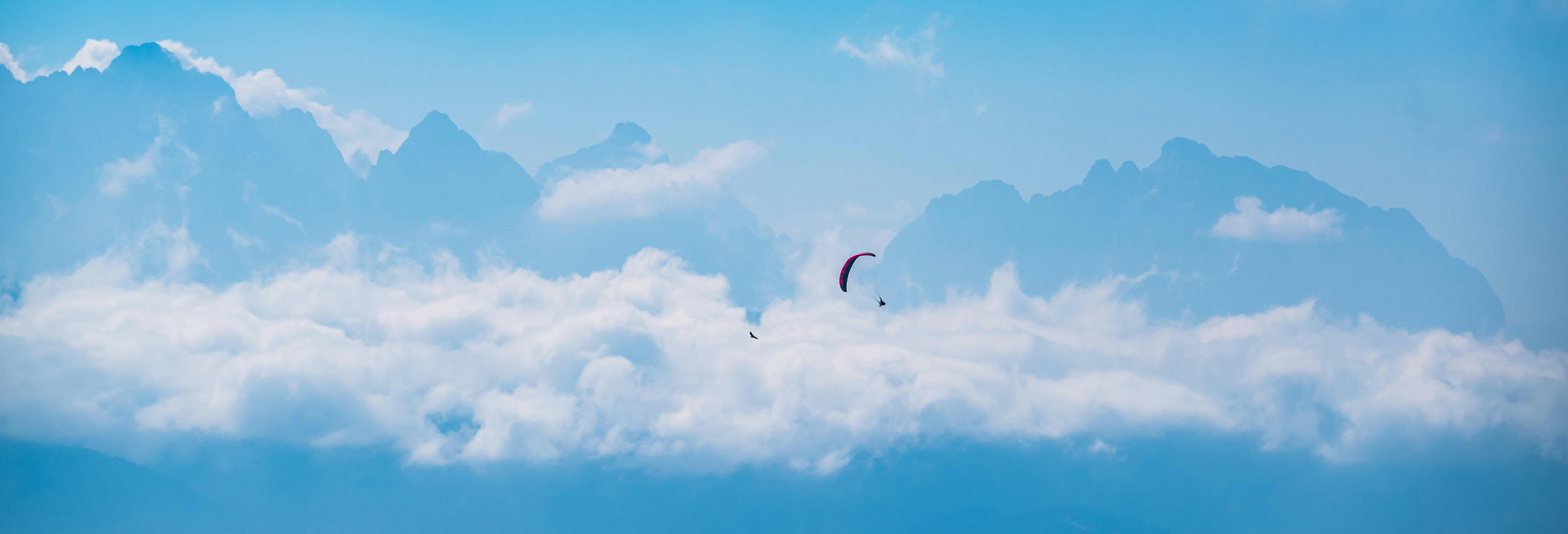 person in parachute under blue sky and white clouds during daytime