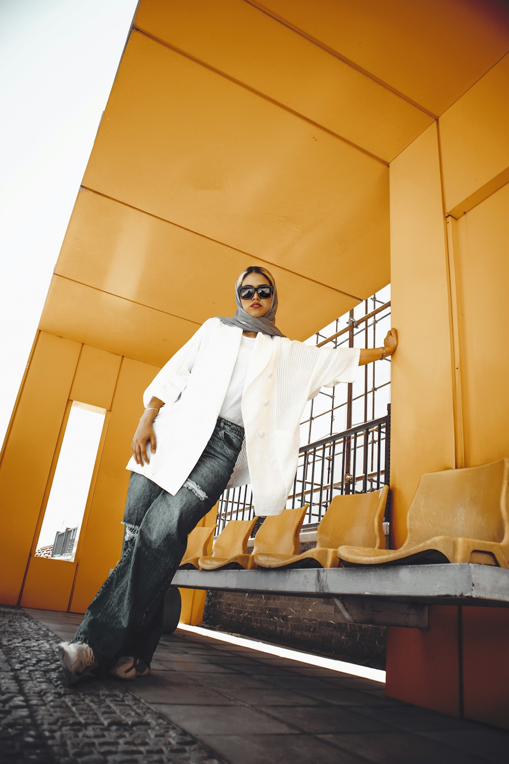 man in white dress shirt and blue denim jeans standing beside yellow wall