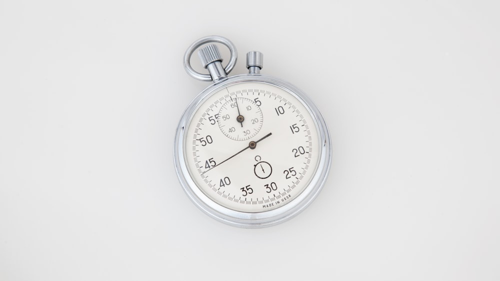Reloj analógico redondo plateado y blanco