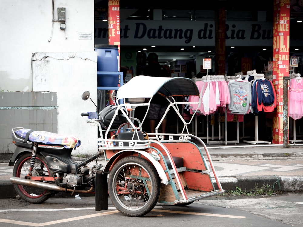 red and black motorcycle parked beside blue and white concrete building during daytime