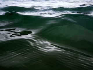 A serene teal and spring green podcast microphone surrounded by soft waves of calming sound