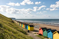 yellow and green houses near sea under white clouds and blue sky during daytime