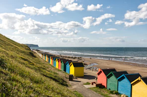 yellow and green houses near sea under white clouds and blue sky during daytime