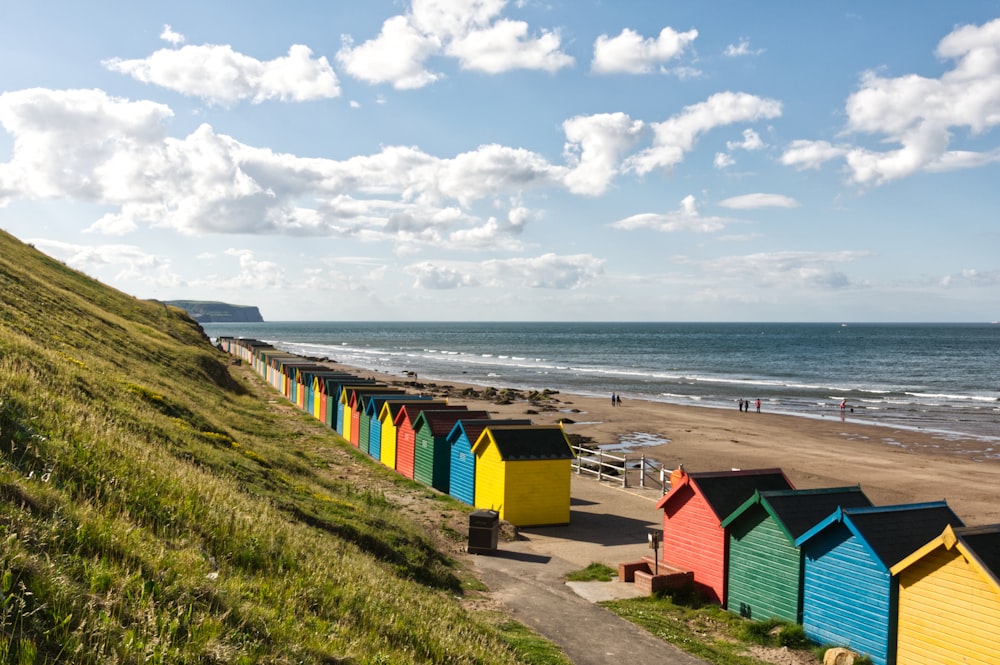 yellow and green houses near sea under white clouds and blue sky during daytime