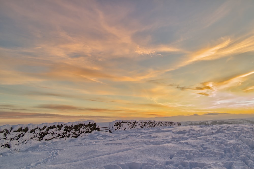 snow covered field under cloudy sky during daytime