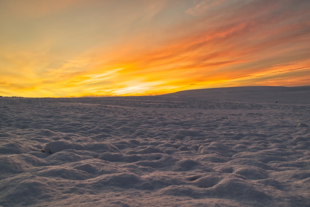 campo coberto de neve branca durante o pôr do sol