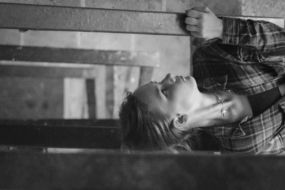 grayscale photo of woman leaning on wall