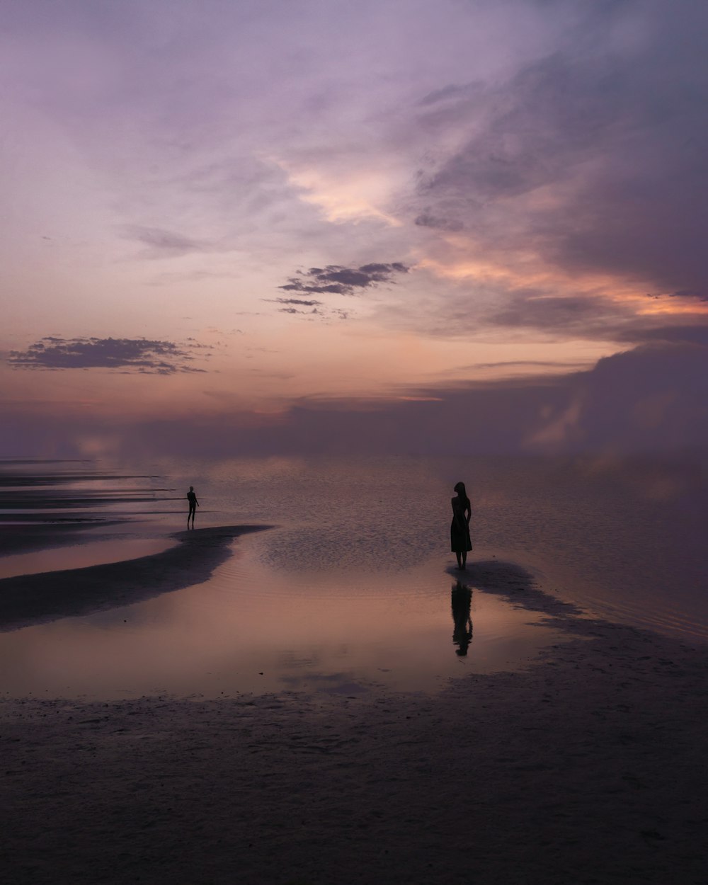 silhouette of person standing on seashore during sunset