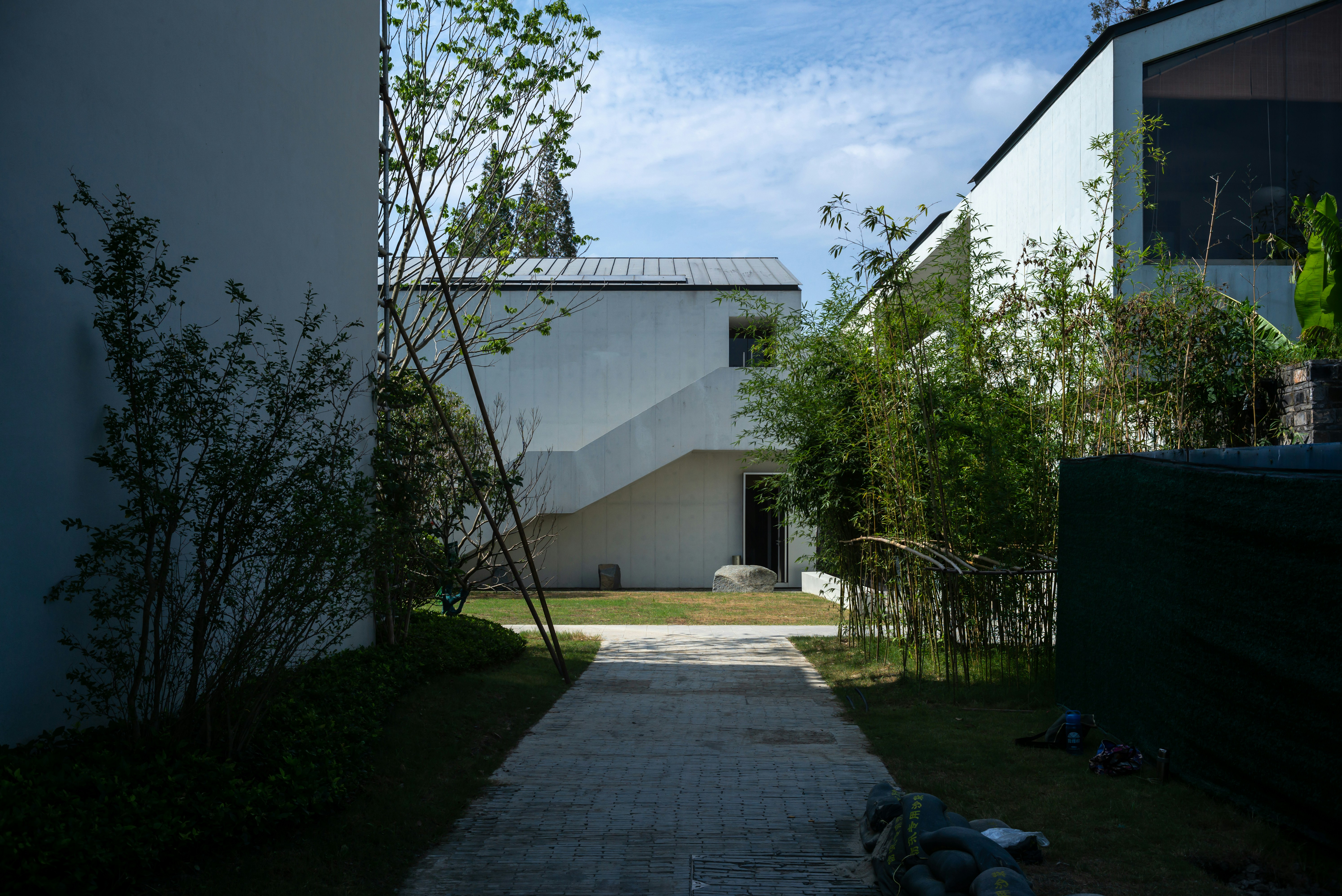white concrete house near green trees under blue sky during daytime