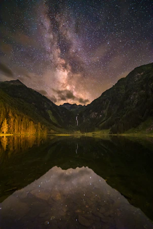 body of water near mountain under starry night