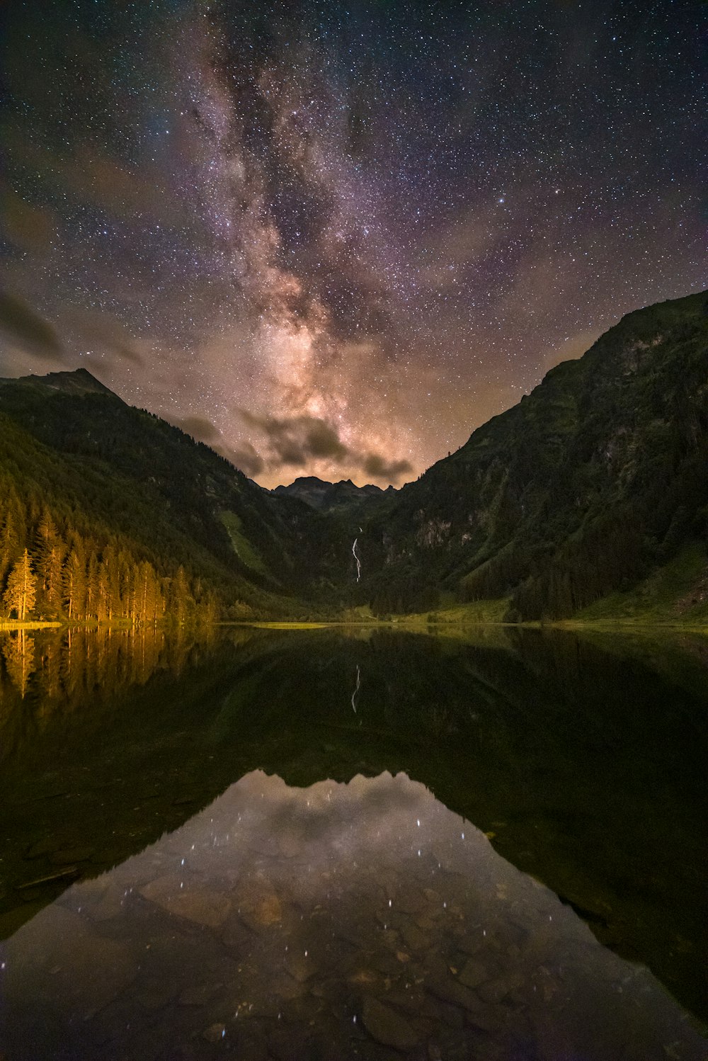 body of water near mountain under starry night