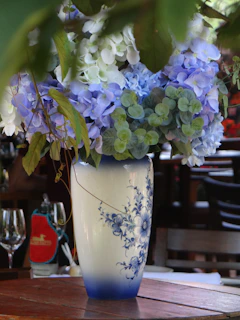 A cheerful ceramic vase with playful splashes of red and blue on a wooden table.