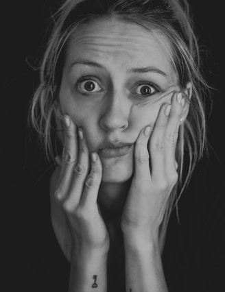 grayscale photo of woman covering her face with her hand